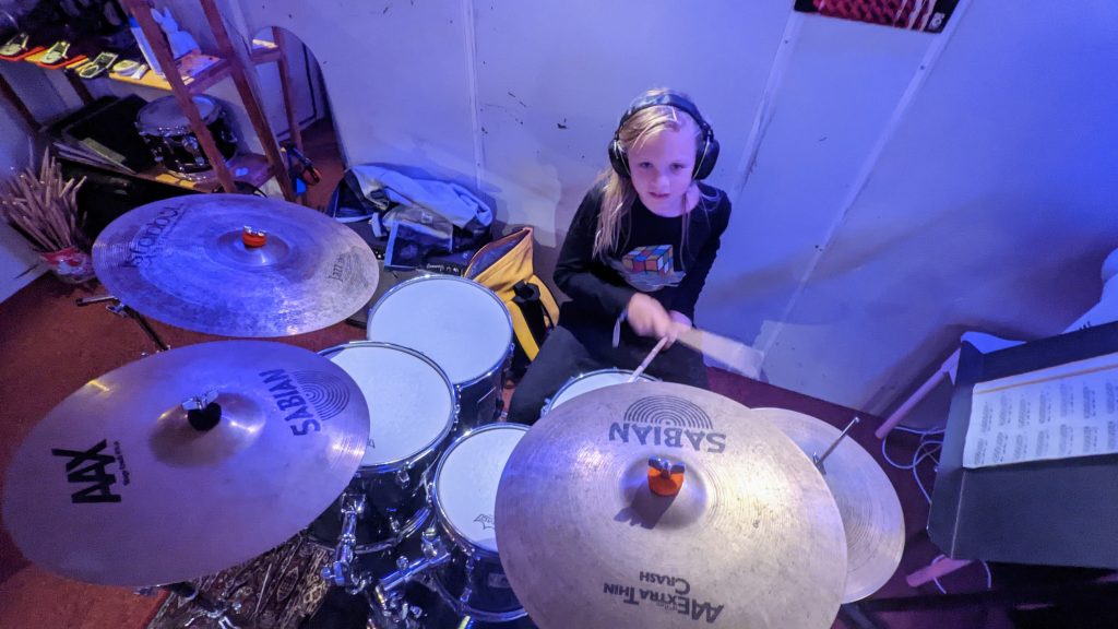 Leerling speelt op een drumstel tijdens de les.